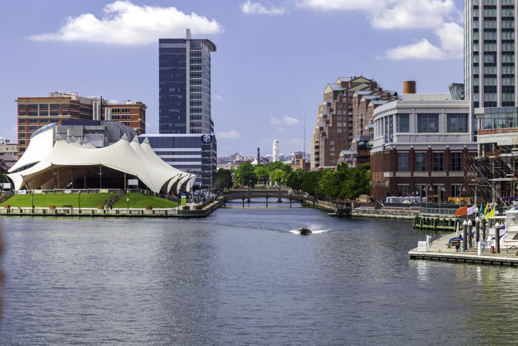 Pier Six Concert Pavilion alongside the  treelined Jones Falls channel at Baltimore Inner Harbor skyline image