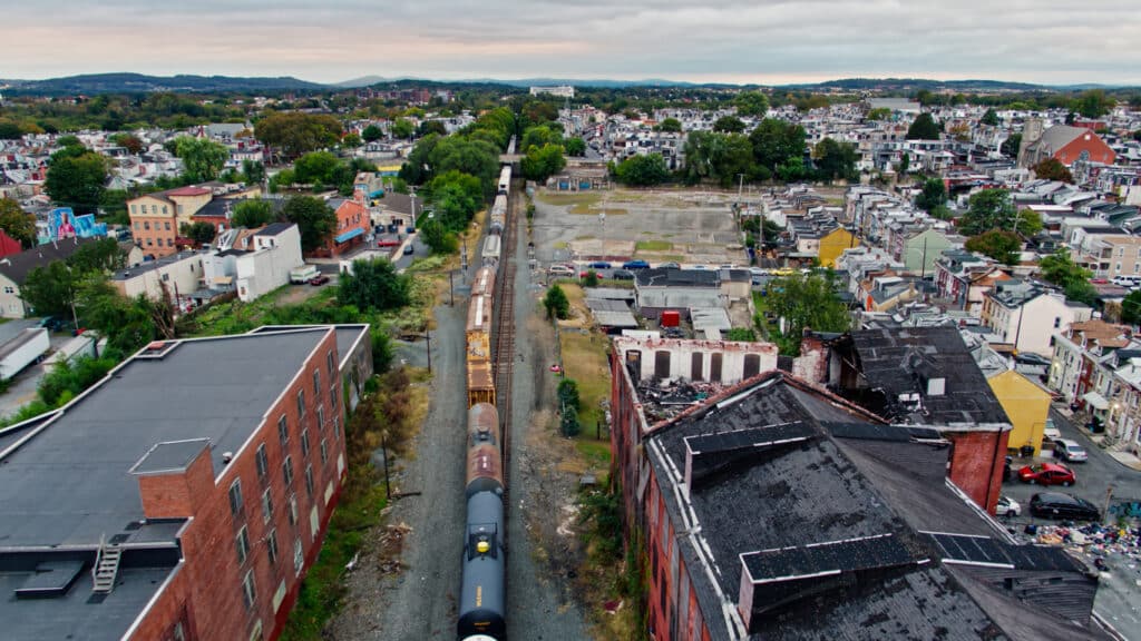 Drone shot of a freight train passing through Reading, Pennsylvania on an overcast afternoon in Fall. 
   
Authorization was obtained from the FAA for this operation in restricted airspace.
